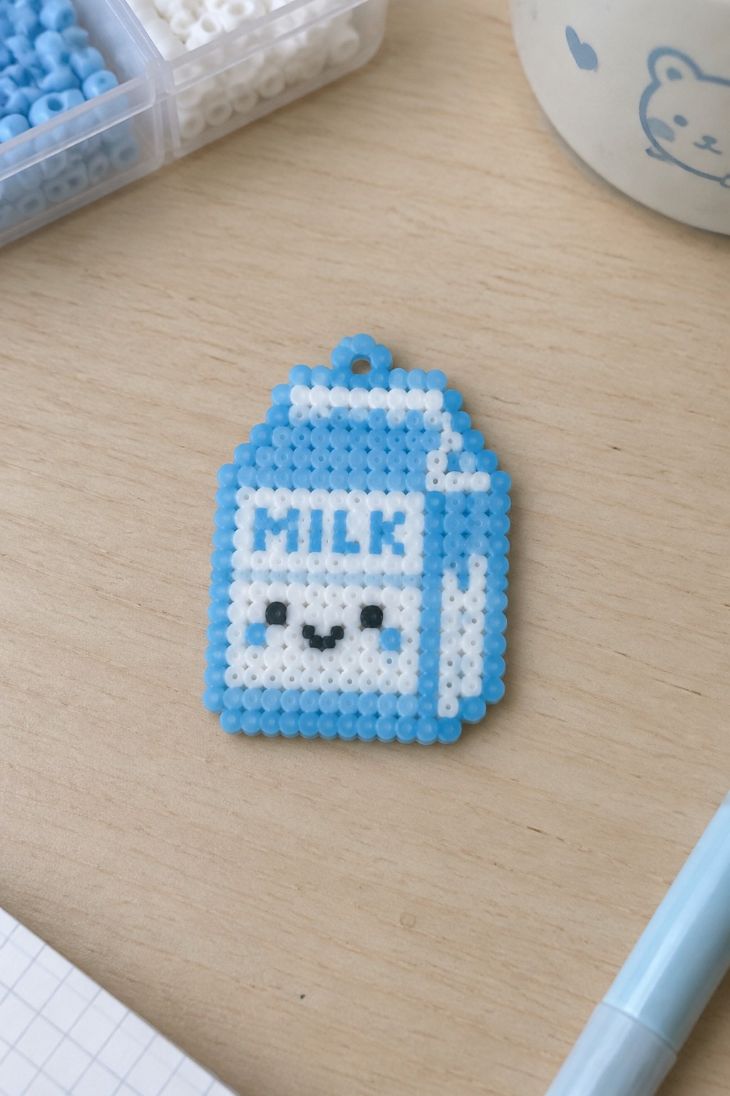 Blue and white perler bead milk carton charm with cute smiling face