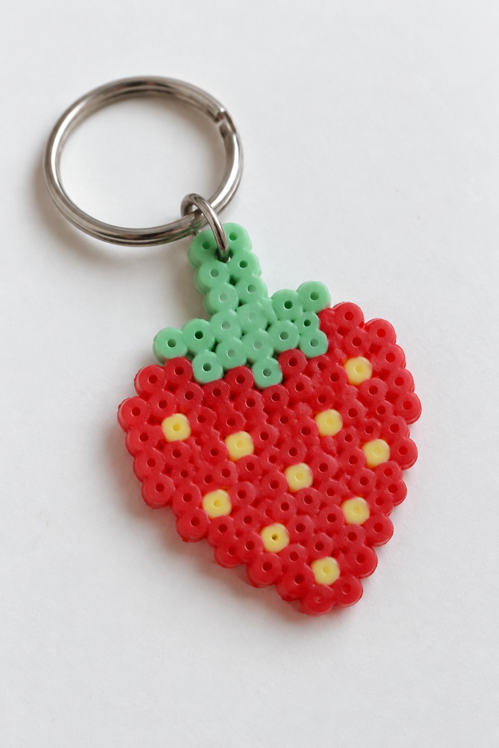 Strawberry keychain of red, green, and yellow perler beads on metal ring