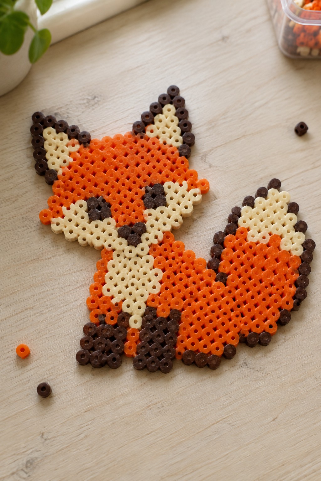 Perler bead fox in orange, brown, and cream on wooden table