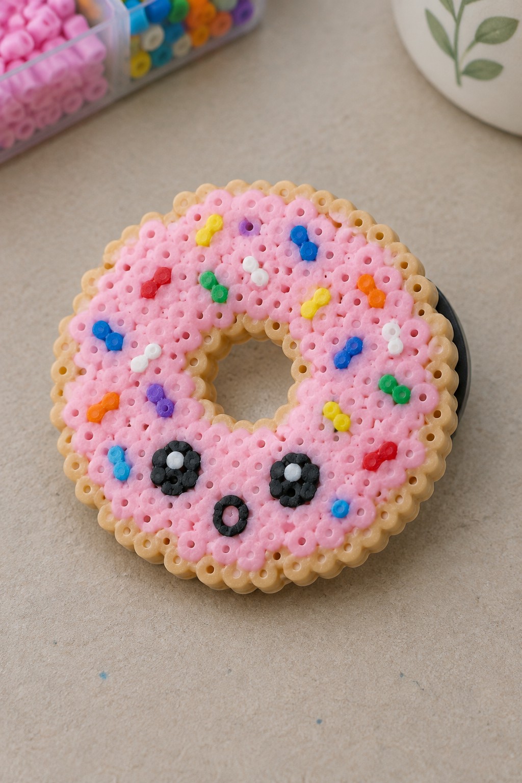 Pink perler bead donut with colorful sprinkles and cute face