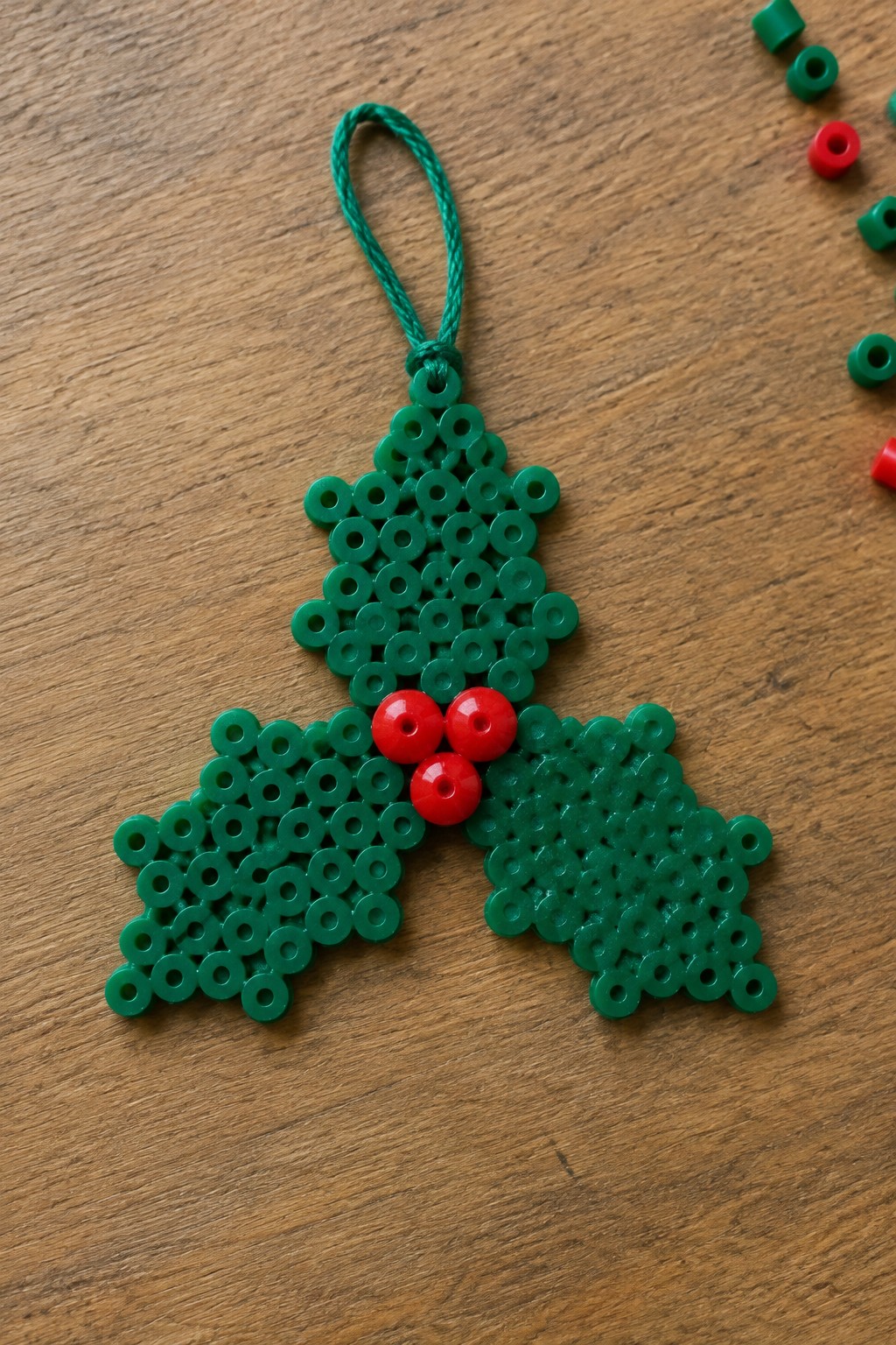 Green perler bead holly ornament with red berries and hanging loop