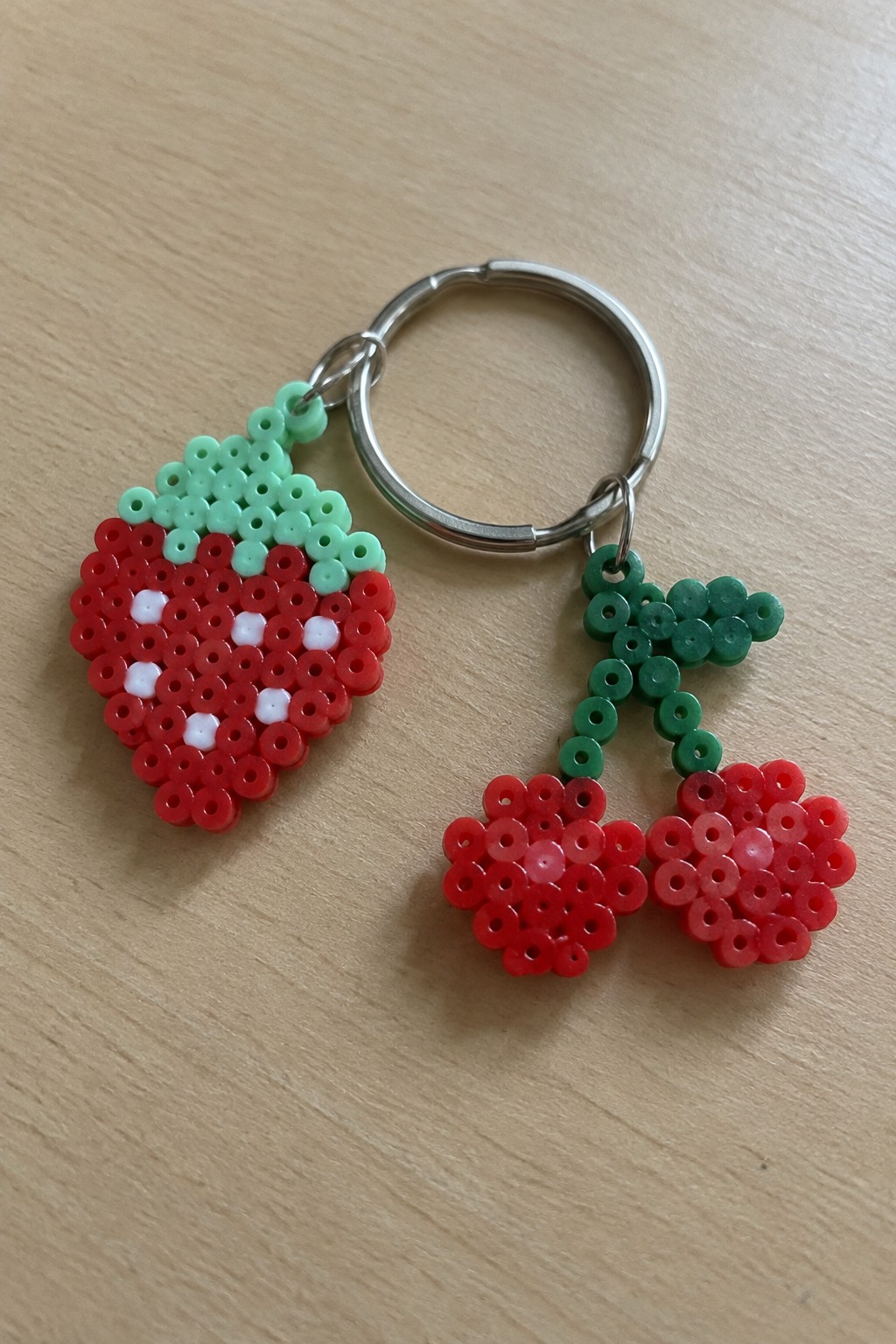 Perler bead keychain with red strawberry and cherry charms on silver ring