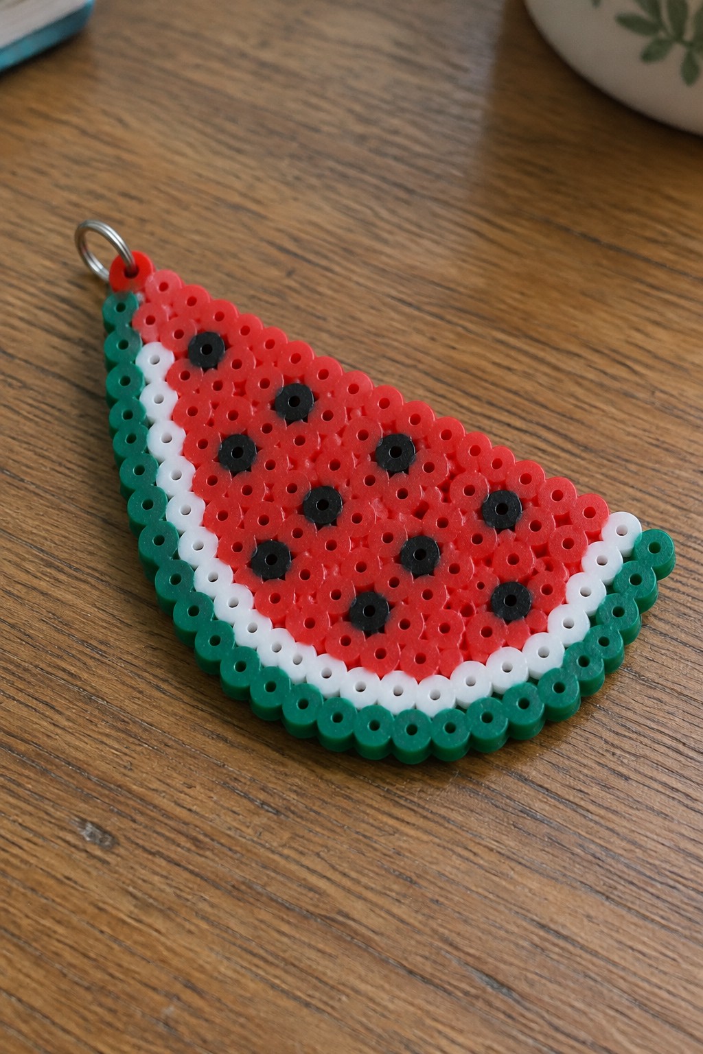 Watermelon slice keychain made from red, black, white, and green perler beads.