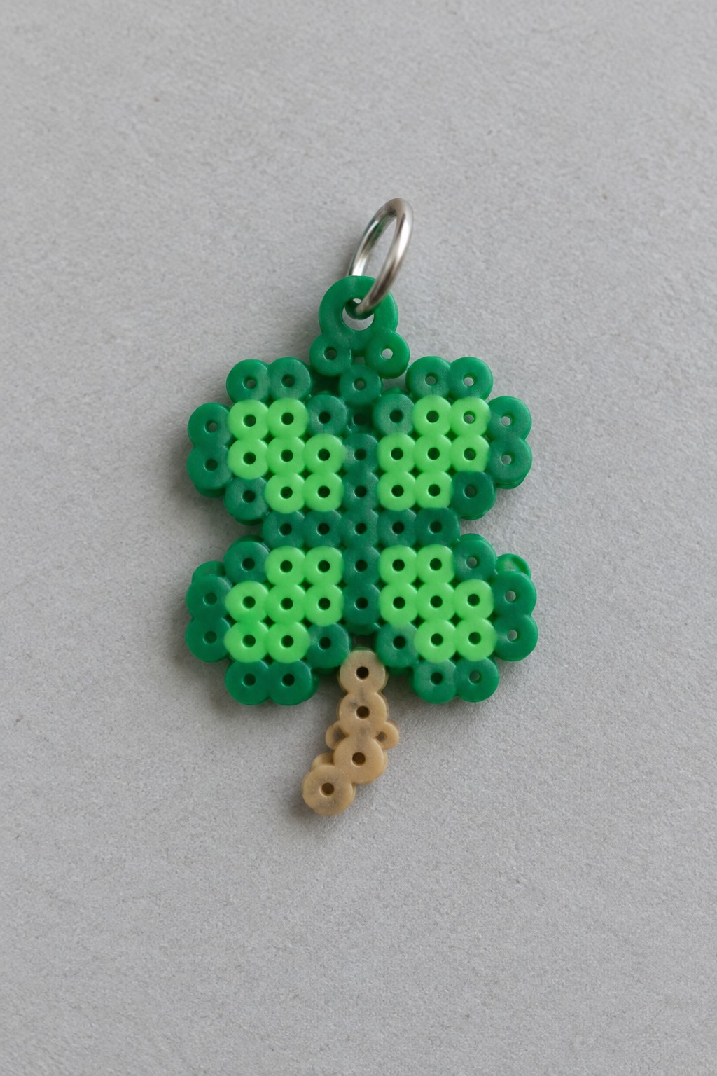 Green perler bead tree with varying shades, beige trunk, and metal ring