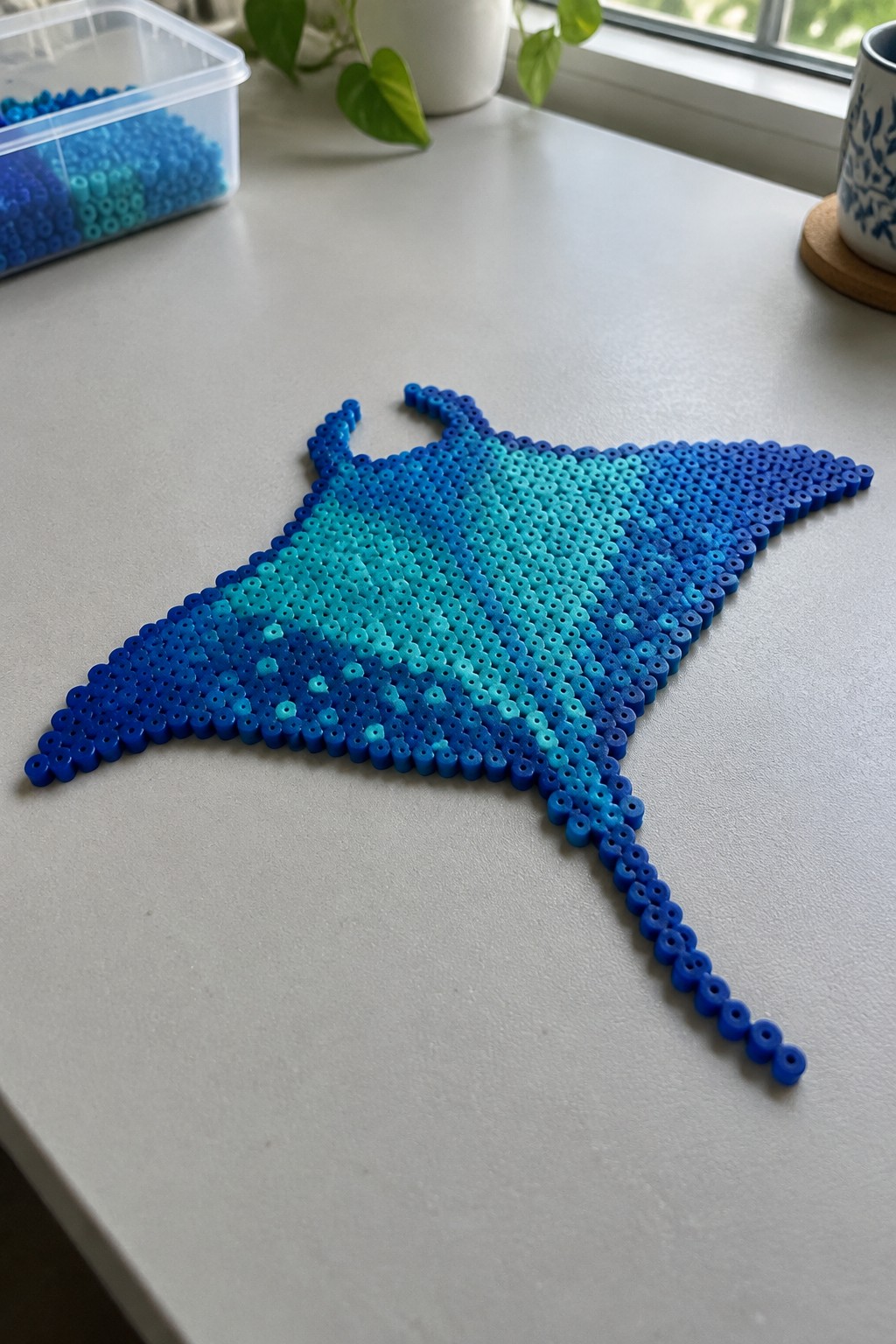 Blue gradient perler bead manta ray with tail on white table