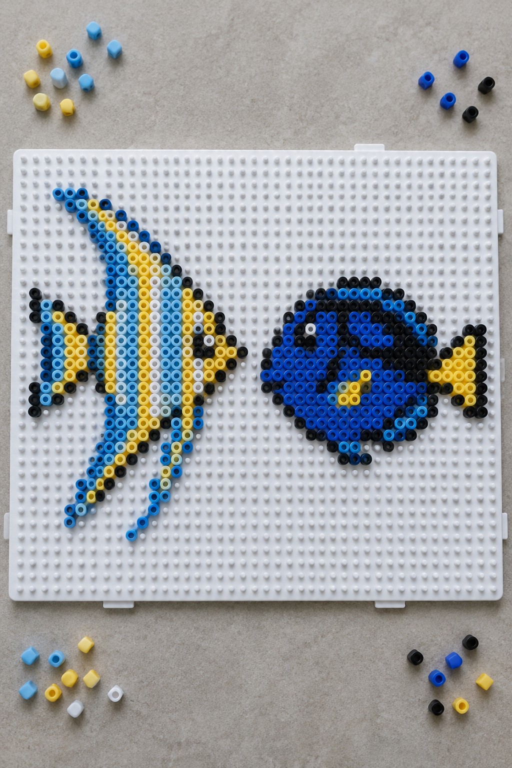 Perler bead fish designs on white pegboard with scattered loose beads around.