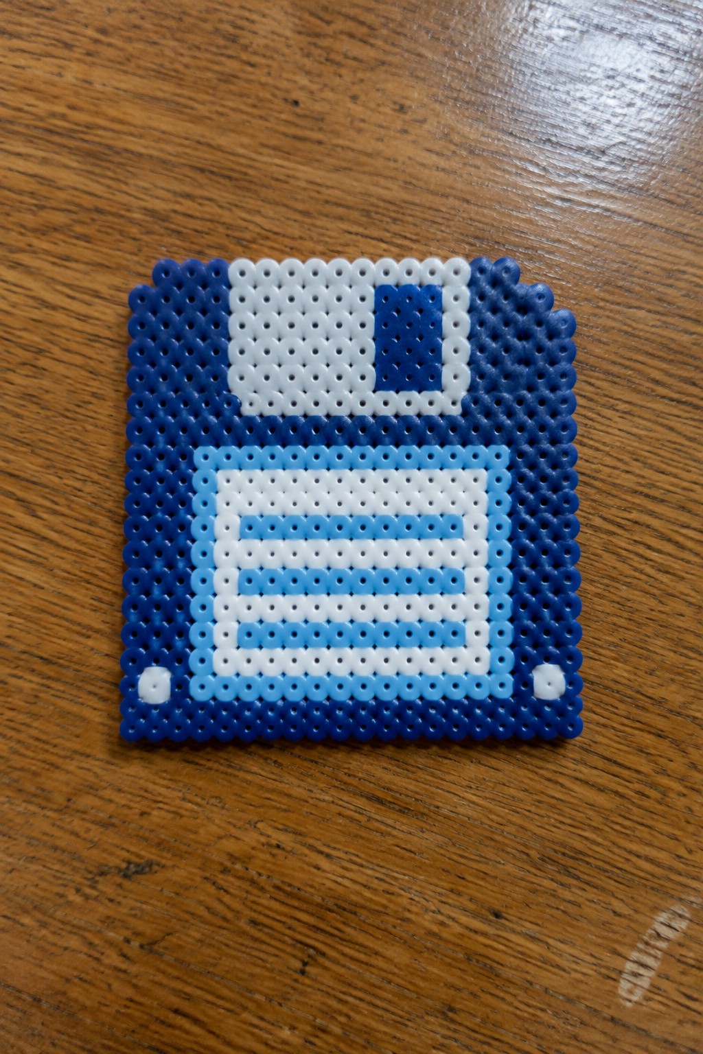 Blue and white perler bead floppy disk on wooden table