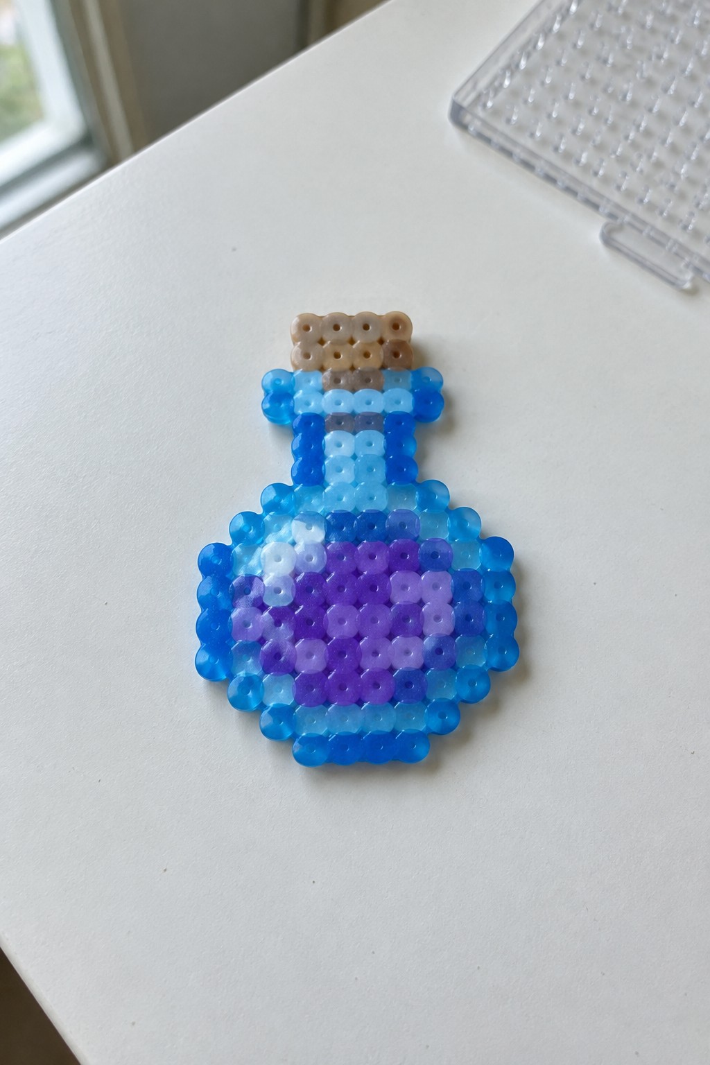 Perler bead potion bottle with blue-purple gradient body and brown cork stopper