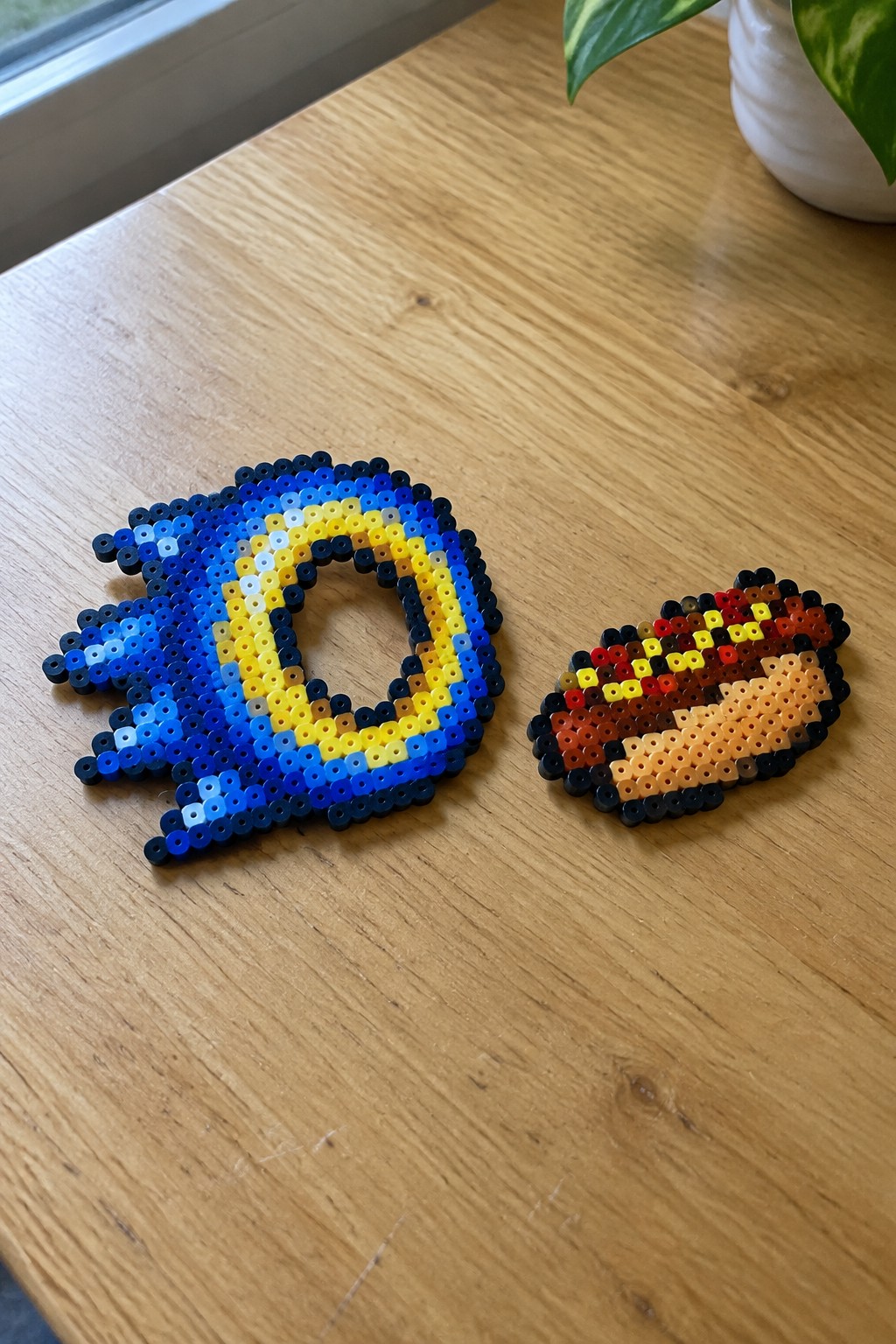 Perler bead Sonic the Hedgehog head and hamburger on wooden table
