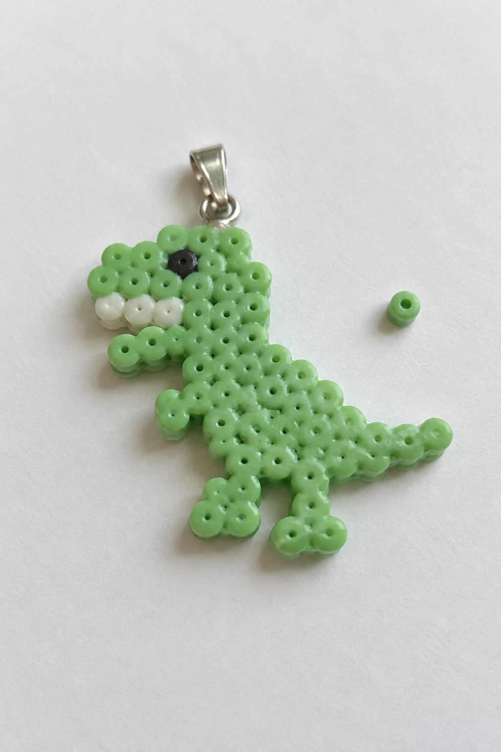Green perler bead T-Rex pendant with white teeth, black eye, silver bail