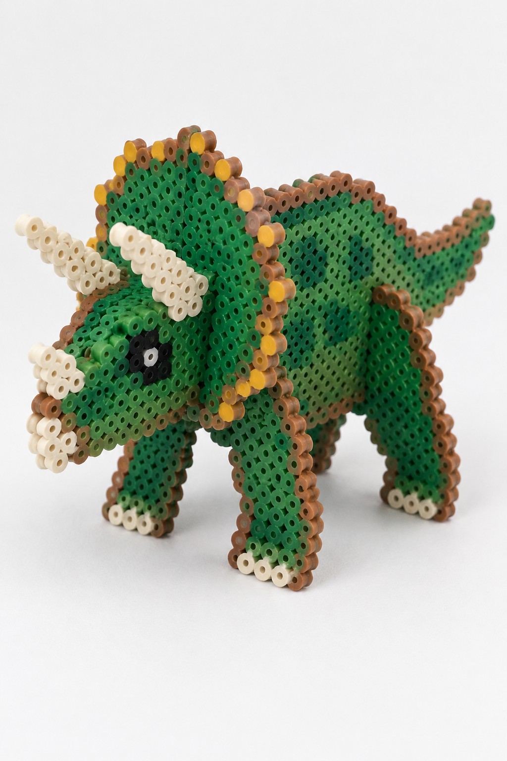 Green perler bead triceratops with brown edges, yellow frill, and white horns.