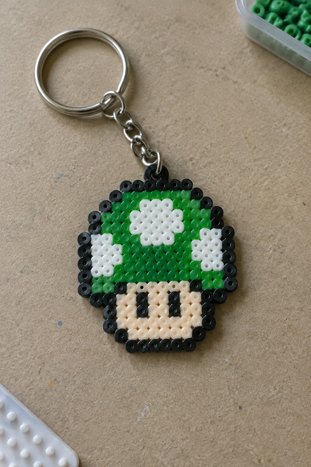 Perler bead keychain of green 1-Up mushroom with white spots and black outline