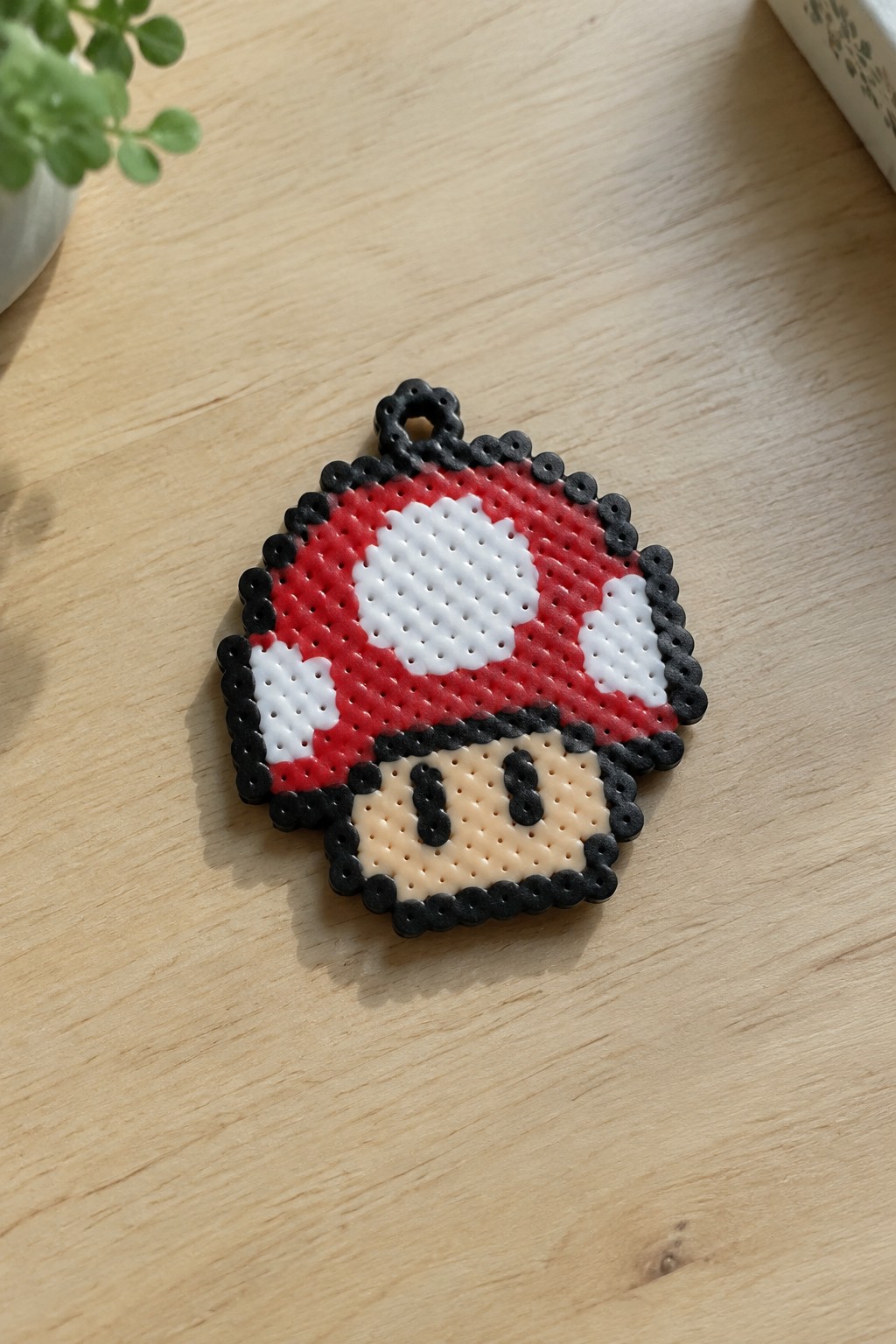 Fused Perler bead Mario mushroom with red cap, white spots, black border, beige face, and top hanging loop.