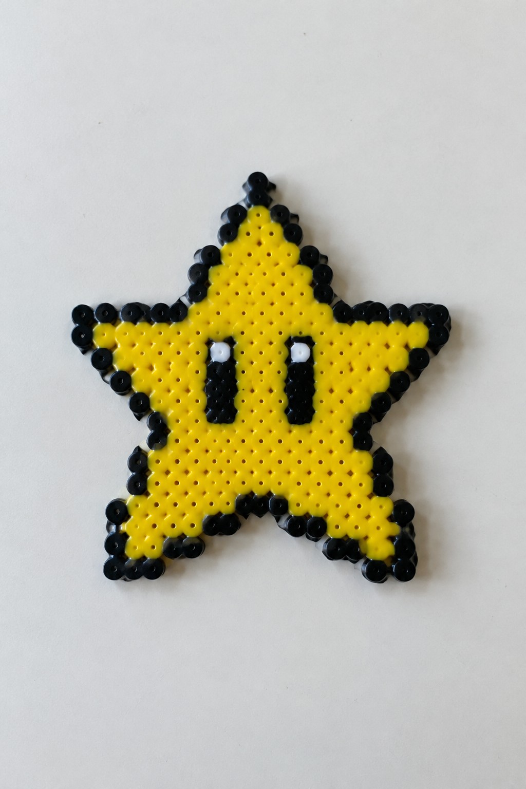 Yellow star perler bead art with black outline and pixelated eyes