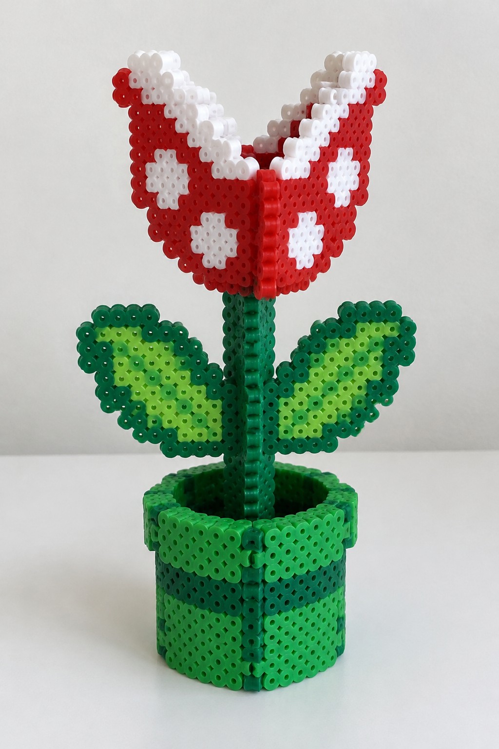 Perler bead Piranha Plant with red spotted head, green stem, and leaves in pot