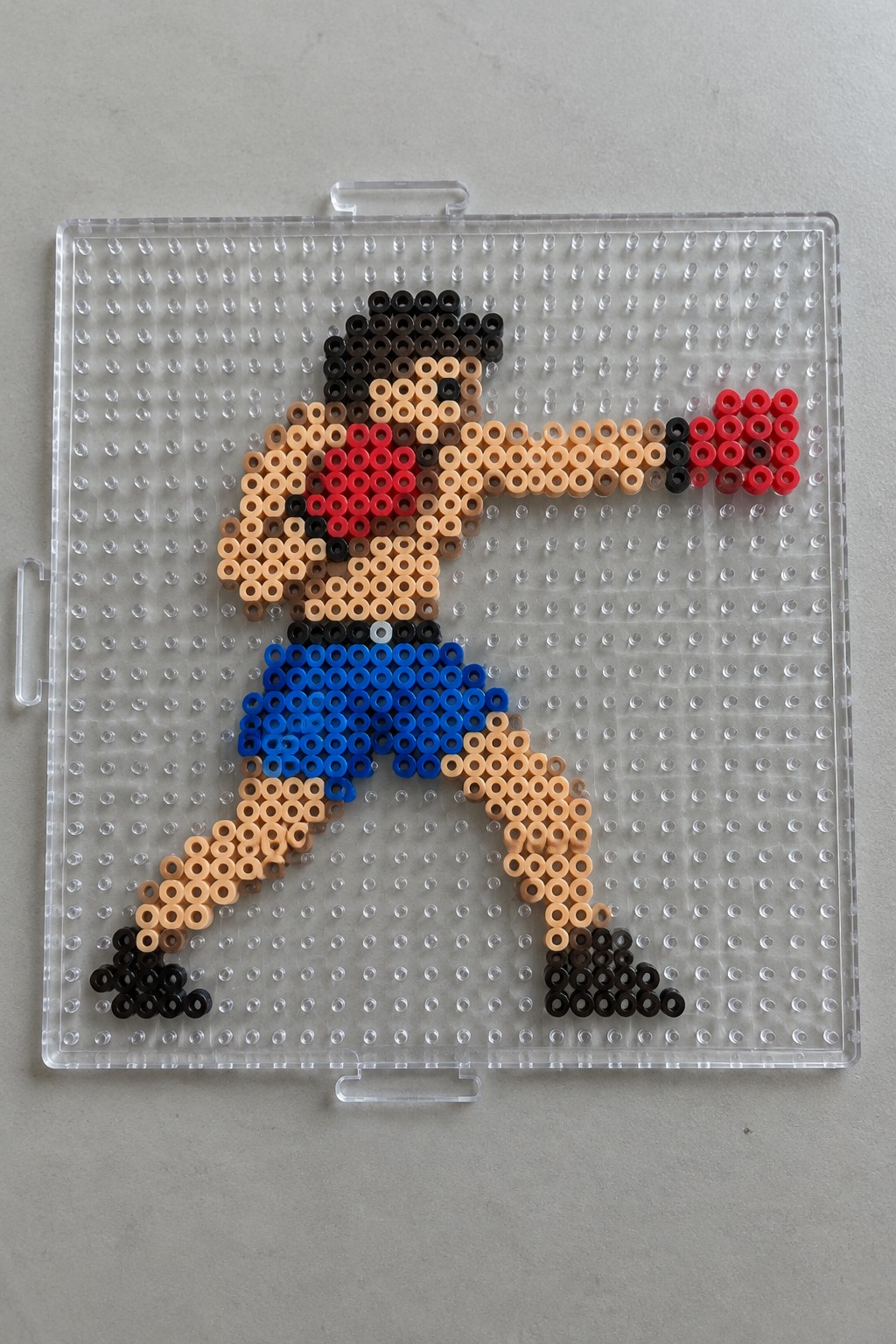 Perler bead boxer with red gloves and blue shorts on clear pegboard